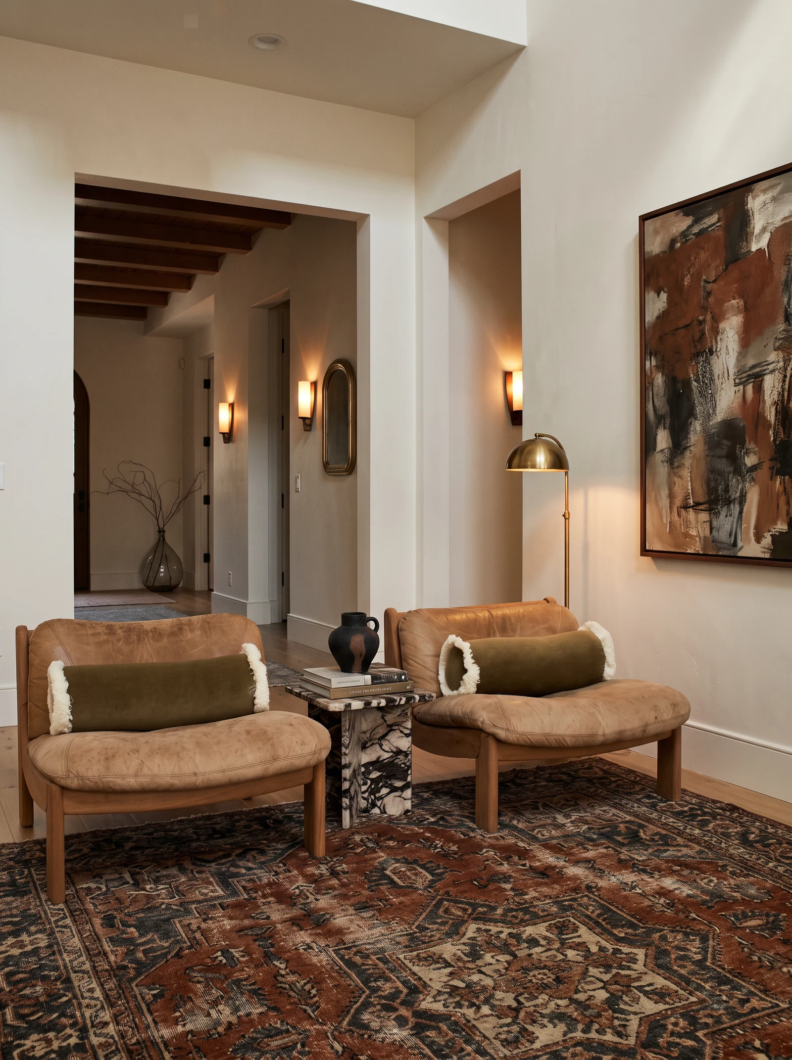 Elbow Park seating area with two vintage leather chairs, bolster pillows, a marble side table and an abstract painting