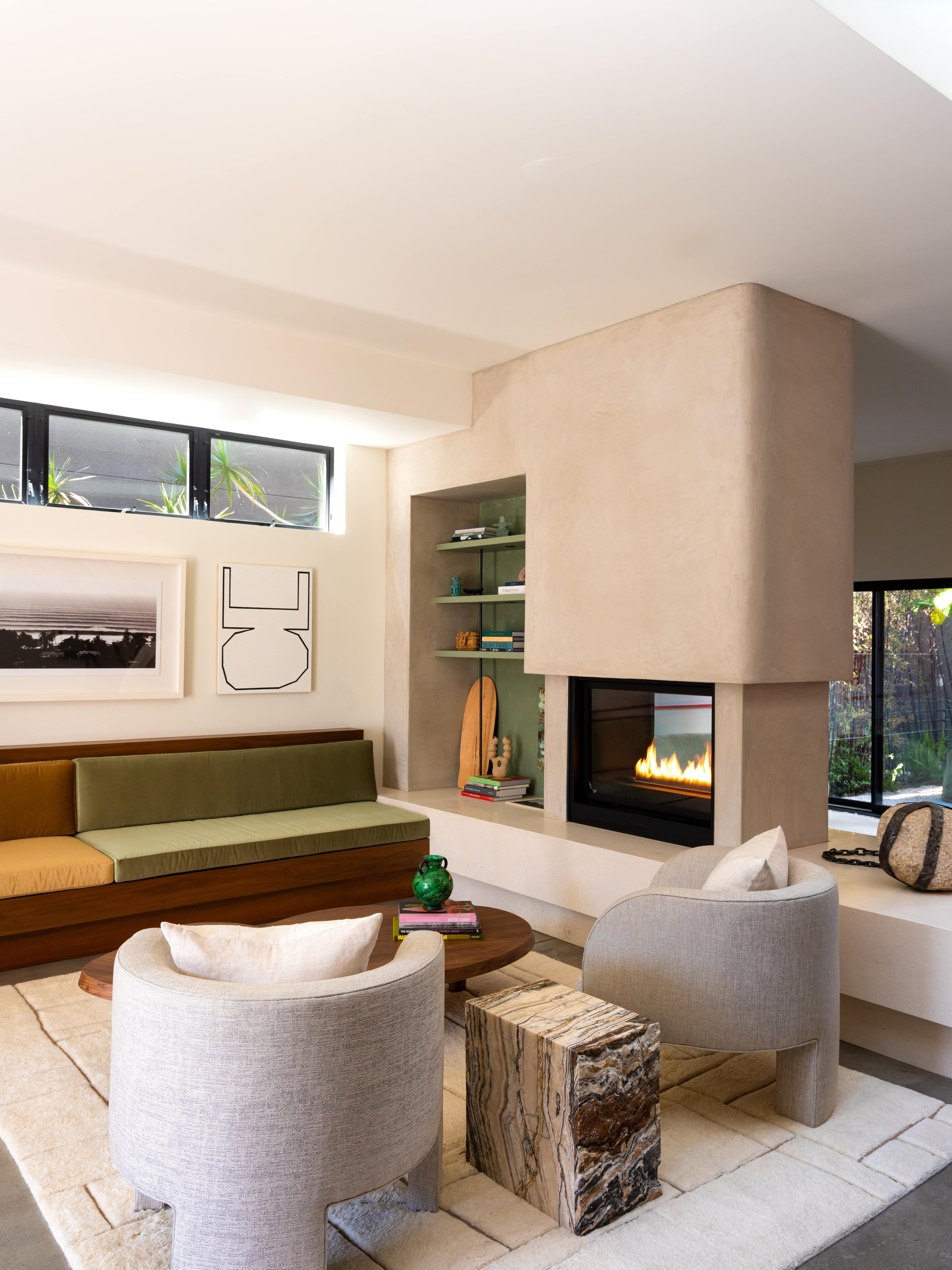 Venice Canals living room with a plaster fireplace, olive and ochre velvet banquette, and rounded linen armchairs